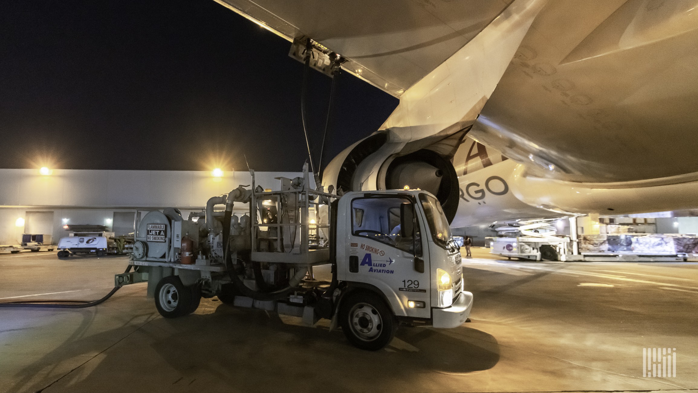 A fuel truck refills a plane at night.