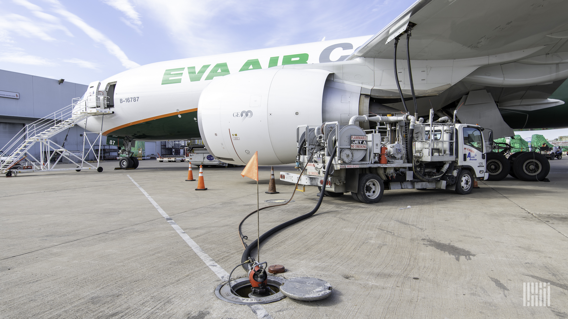 A large cargo jet getting refueled by a truck at the airport.