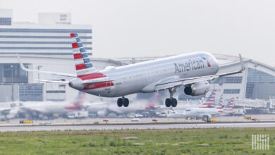 A tri-colored American Airlines jet lands on a runway.