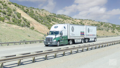 A white and green Old Dominion tractor pulling two Old Dominion LTL trailers on a highway
