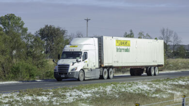 A white J.B. Hunt tractor pulling a J.B. Hunt intermodal container on a highway
