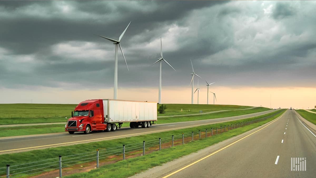 Truck driving on highway with wind turbines