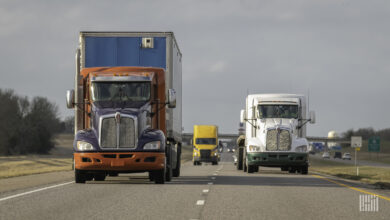 Three trucks drive toward the camera along a two-lane interstate